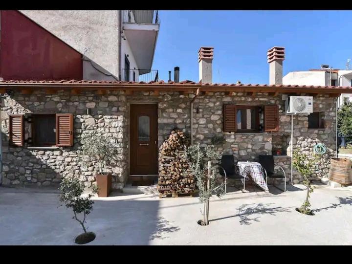 een stenen huis met een tafel en stoelen ervoor bij Το πατρικό του Σταύρου. in Mouzákion