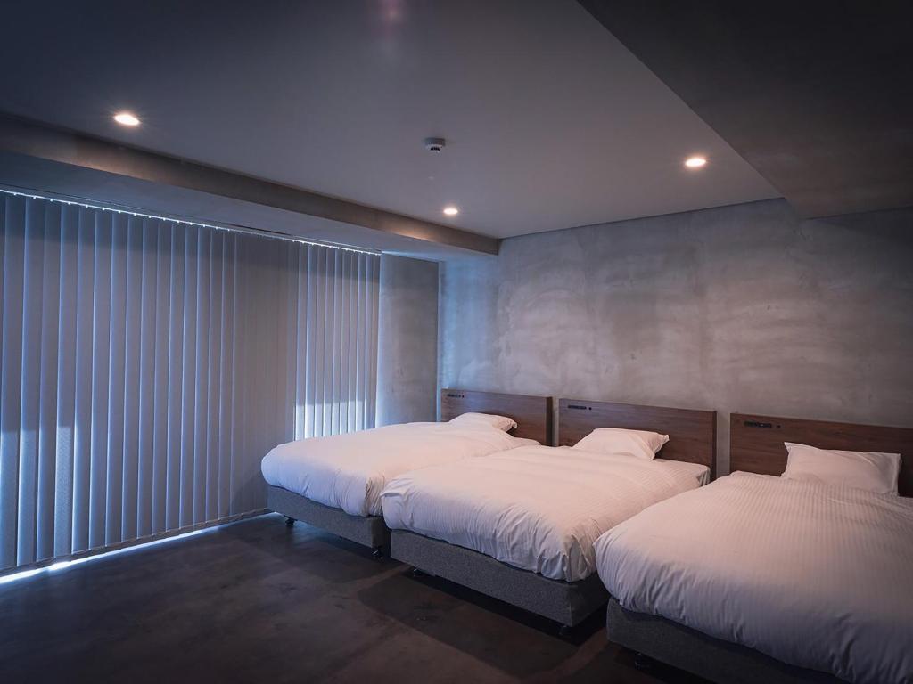 1 dormitorio con 2 camas y ventana en maejima Hotel en Naha