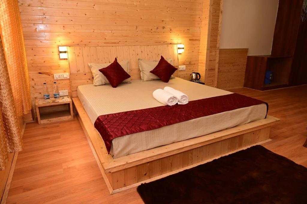 a bedroom with a bed with two towels on it at Great Himalayan Nature View Resort in Banjār