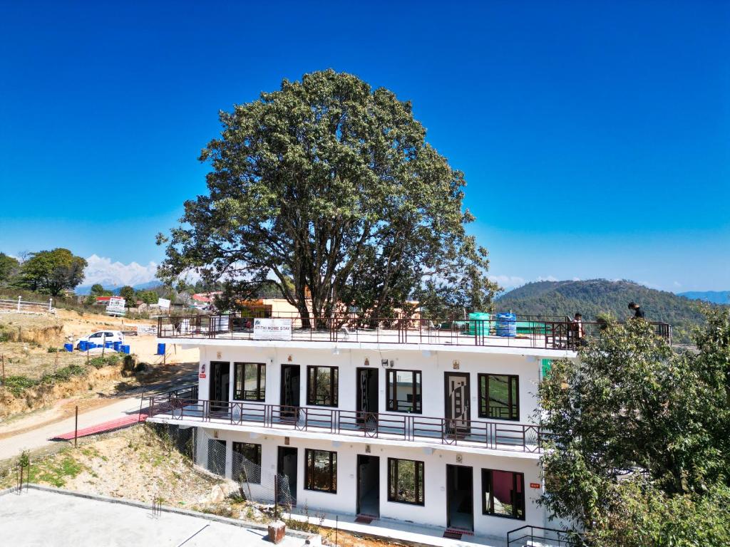 un edificio bianco con un albero sopra di Atithi Home Stay - Himalayas view a Chaukori