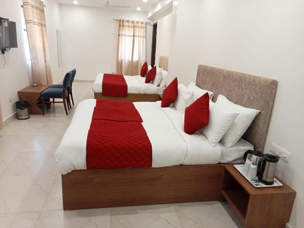una camera d'albergo con due letti con lenzuola rosse e bianche di Hotel Fortune Residency a Nuova Delhi