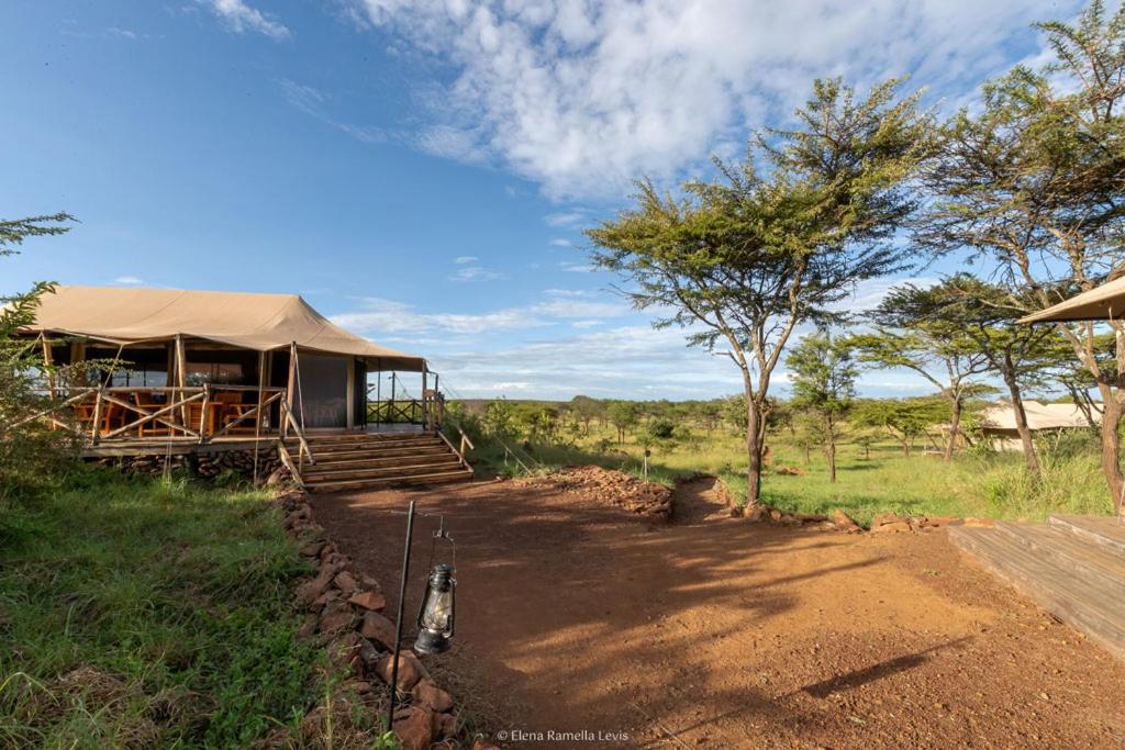 a building with a tent in the middle of a field at Serengeti Kifaru Tented Lodge in Mugumu