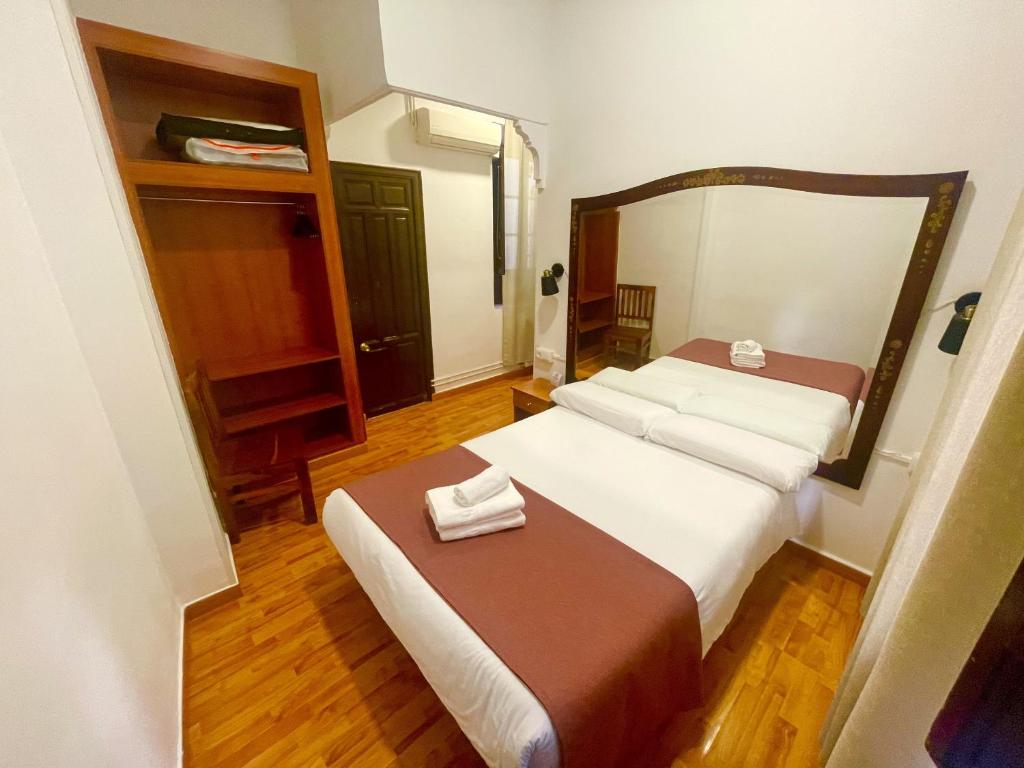 Dormitorio pequeño con cama y espejo en Arteaga Hostal & Baños Arabes Elvira, en Granada