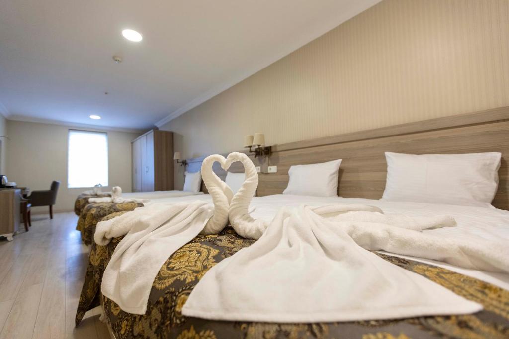 イスタンブールにあるWorld Point Hotel Besyolのホテルの部屋のベッド2台に白鳥2羽が座っています。