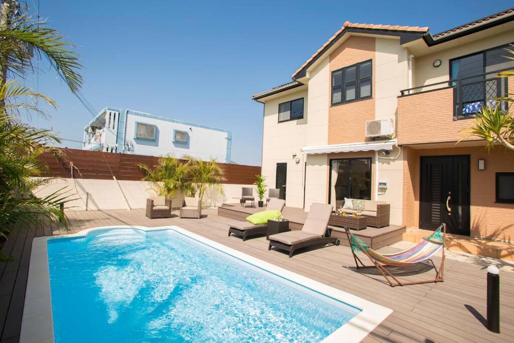 a swimming pool in front of a house at 最大11名宿泊可！憧れのプール付き一軒家をあなただけの貸切に。～ここから始まる贅沢な南国ライフを～ in Yabu