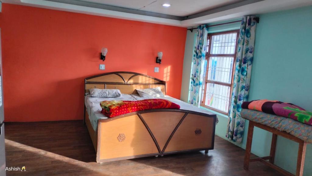 1 dormitorio con 1 cama con pared de color naranja en Heena Guest House, en Dharamshala