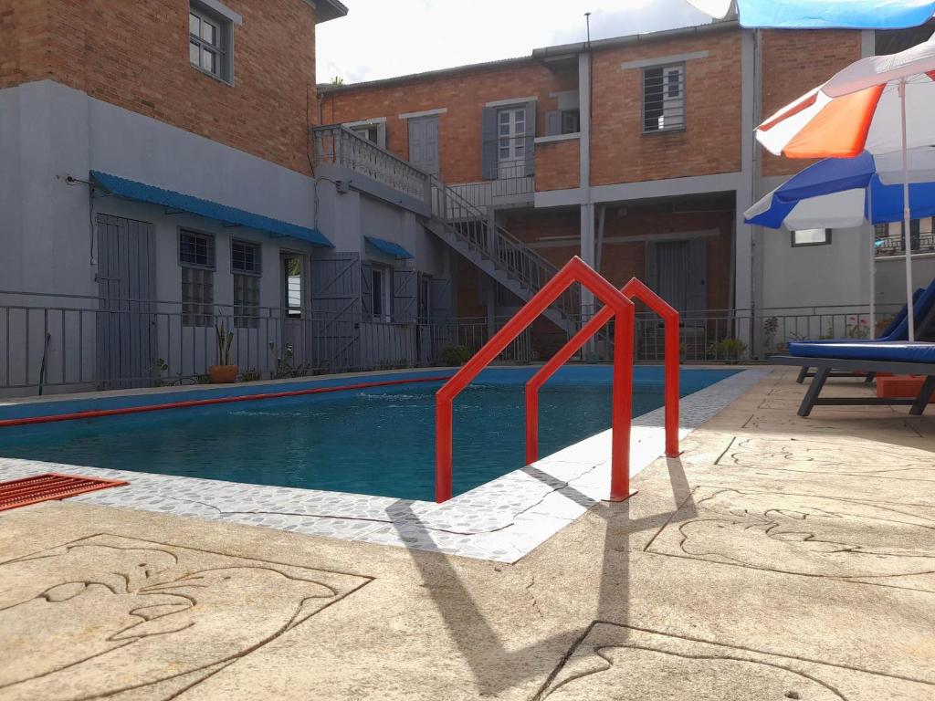 安齊拉貝的住宿－Chez Joël，一座游泳池,旁边是一座建筑,上面有红色栏杆
