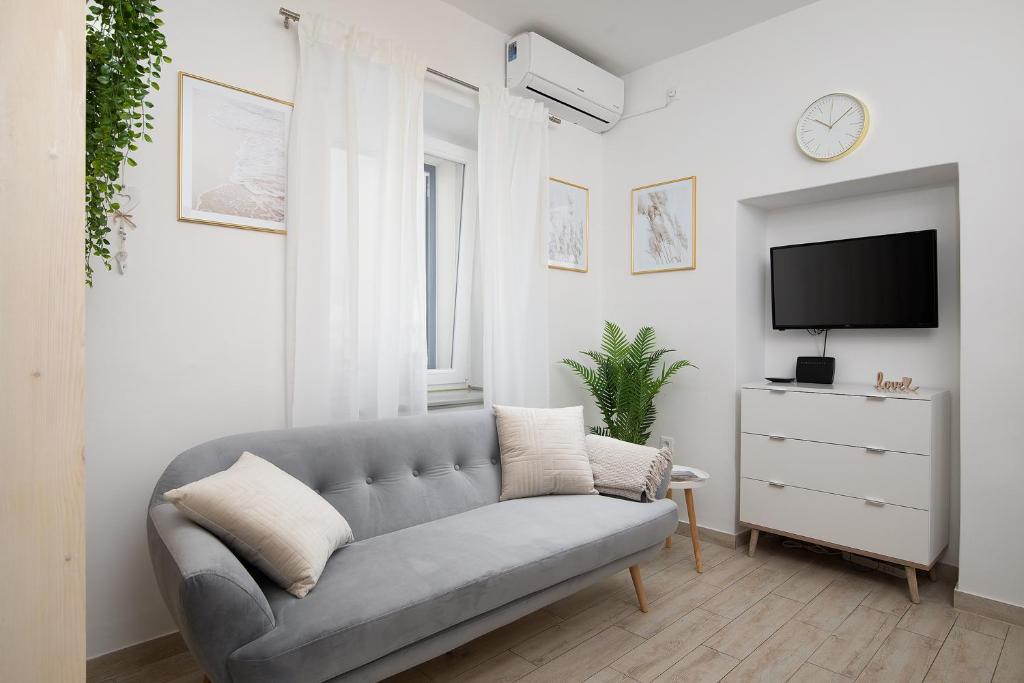 a living room with a couch and a tv at Charming Apartment next to Roman Amphitheater in Pula