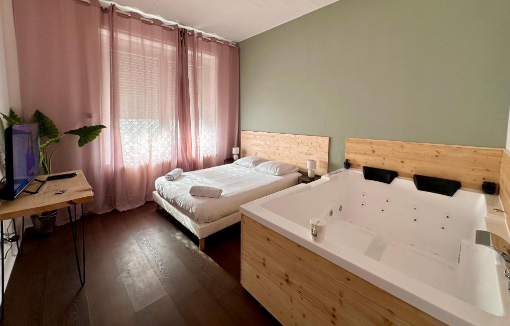 ein Badezimmer mit Badewanne und ein Bett in einem Zimmer in der Unterkunft A0 Grand Appartement, Jaccuzi, et extérieur Thermal Artem à 200m in Nancy