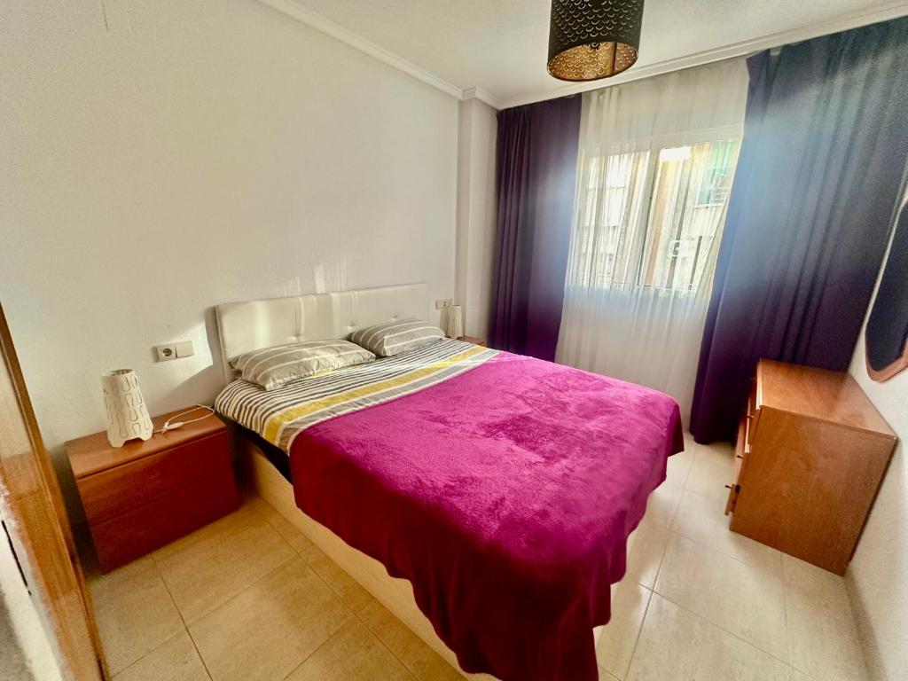 a bedroom with a large bed with a pink blanket at La Loma 72 in Torrevieja