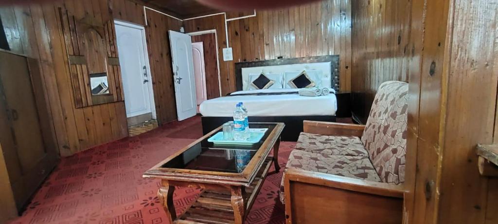 a bedroom with a bed and a table and a couch at Hotel New Broadway in Patnitop