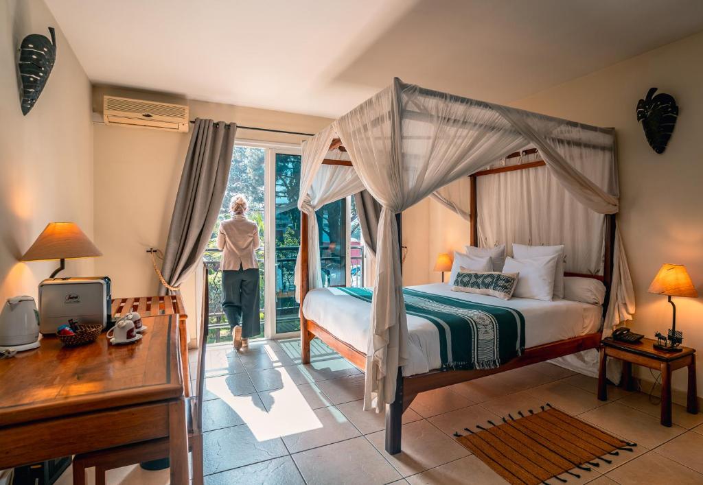 a bedroom with a canopy bed and a person standing outside at Relais des Plateaux & Spa&ndash; Ivato International Airport in Antananarivo