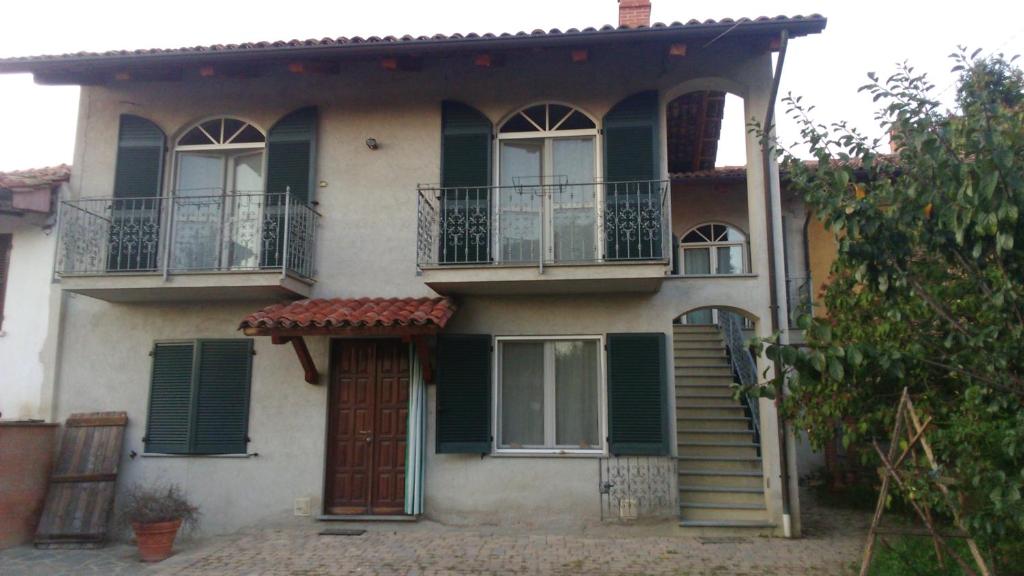 a house with green shutters and a staircase on it at La Casa Di Baba' in Alfiano Natta