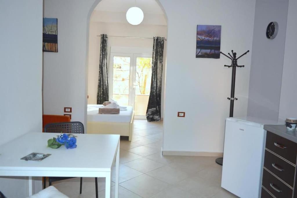 a kitchen with a white table and a room with a bed at Pogradec Sunilio Apartment in Pogradec