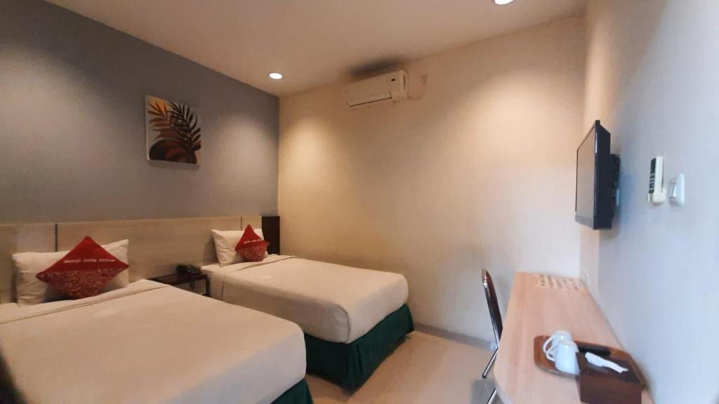 a hotel room with two beds and a desk at Hotel Cepu Indah 2 in Cepu