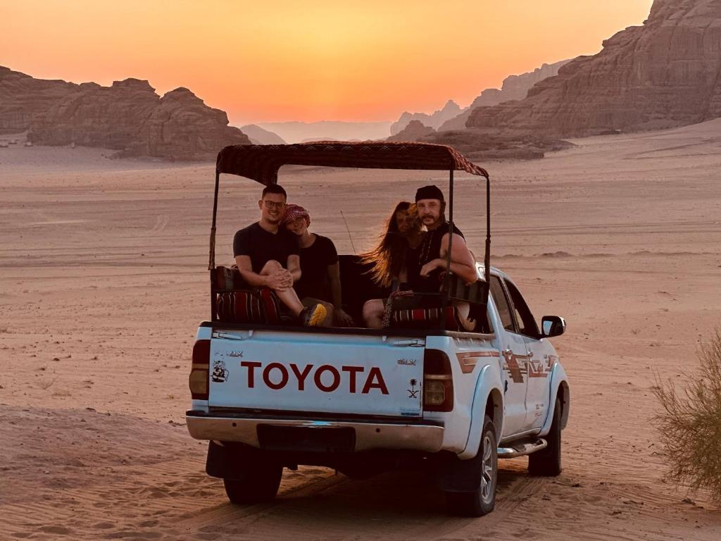 a group of people sitting in the back of a truck in the desert at Rum Marriott luxury camp in Wadi Rum