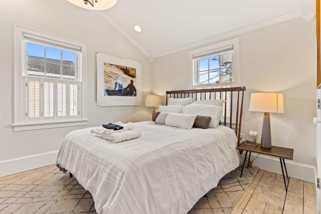 a white bedroom with a large bed and two windows at The Garden Downtown Steps to Waterfront in Newburyport