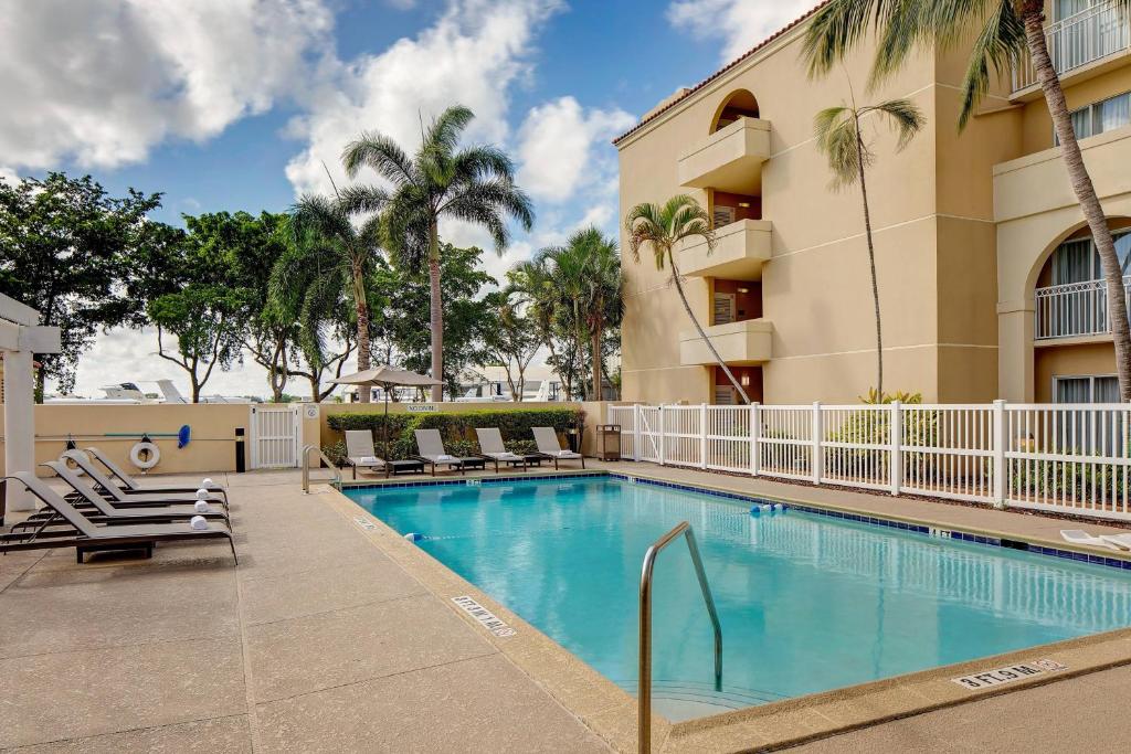 una piscina con tumbonas y un hotel en Courtyard by Marriott Fort Lauderdale North/Cypress Creek, en Fort Lauderdale