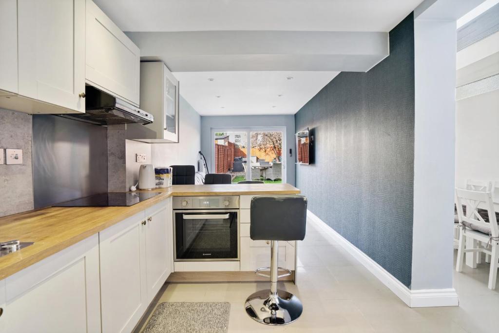 una cocina con armarios blancos y una silla. en 7 Bedroom house with Garden, en Londres