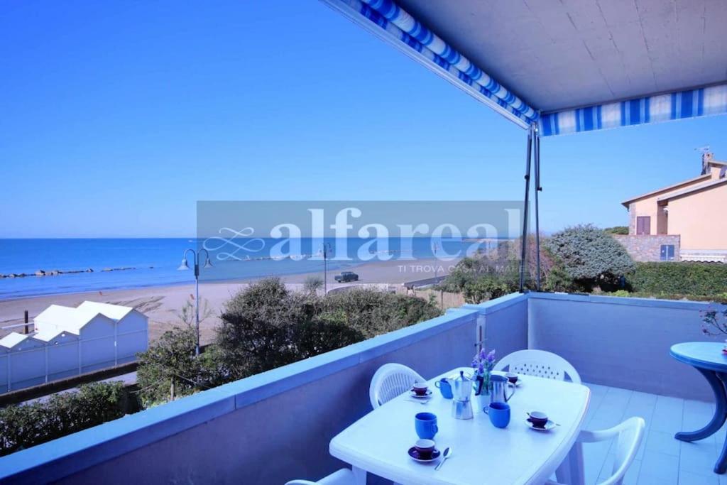 un tavolo e sedie su un balcone con vista sulla spiaggia di LUCIANA 1P terrazza fronte mare e posto auto a Castiglione della Pescaia