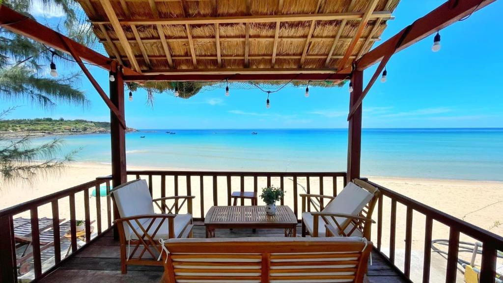 einen Tisch und Stühle auf einem Balkon mit Blick auf den Strand in der Unterkunft Layla Cottage Gành Đá Đĩa in Tuy Hoa