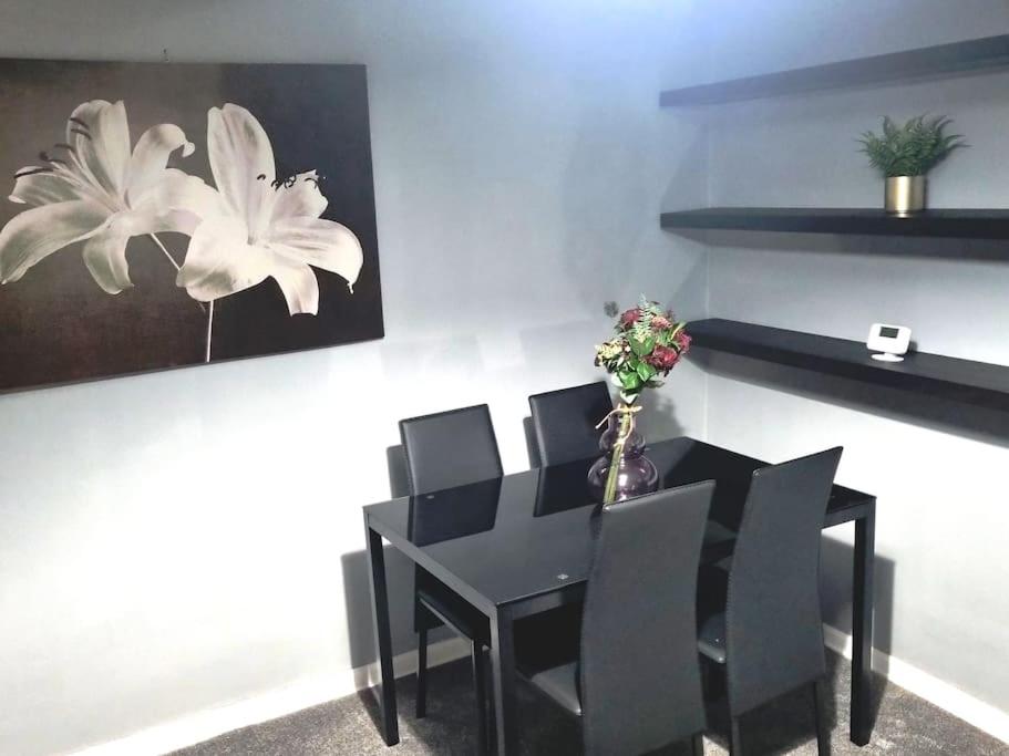 einen schwarzen Esstisch mit schwarzen Stühlen und eine Vase mit Blumen in der Unterkunft Comfy 1st floor flat, sleeps 4 in London