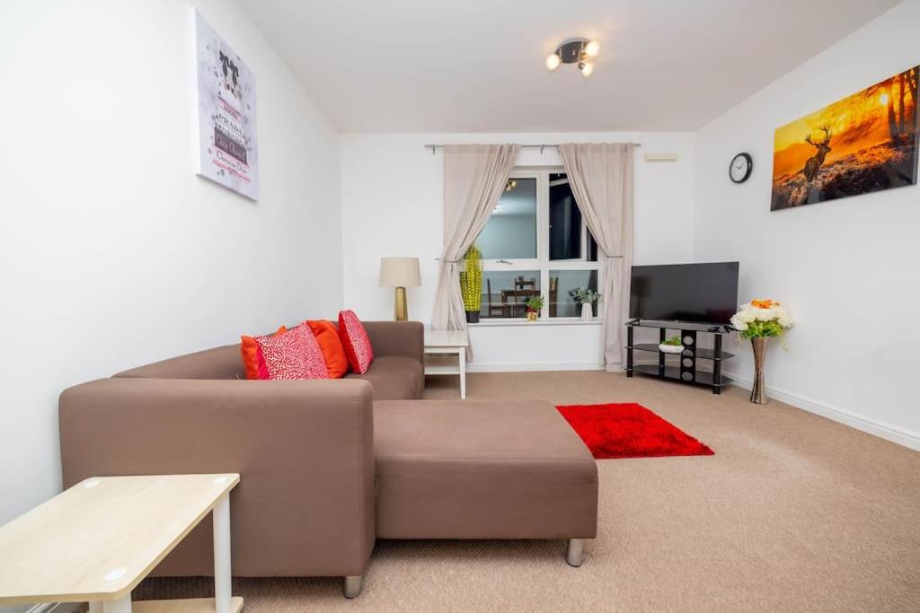 a living room with a brown couch and a red rug at Dannyrex Apartments in Northampton