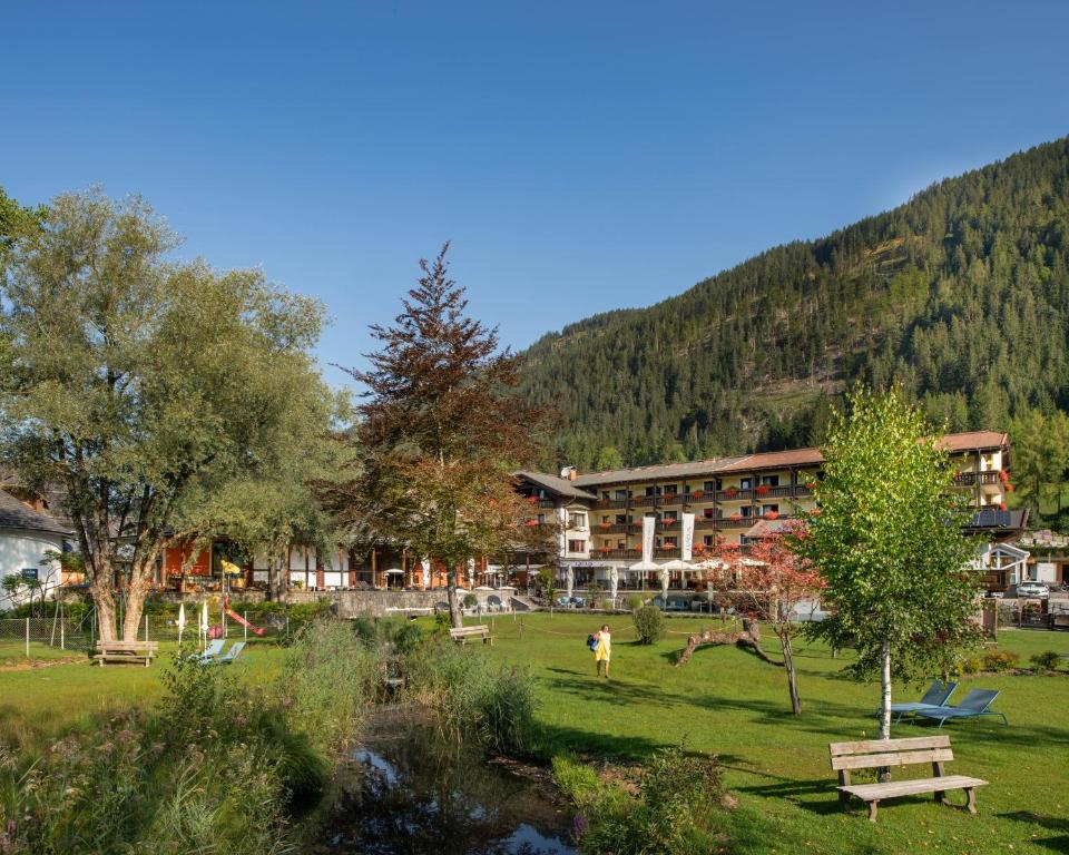 a resort in the mountains with a park with benches at LACUS Hotel am See in Weissensee
