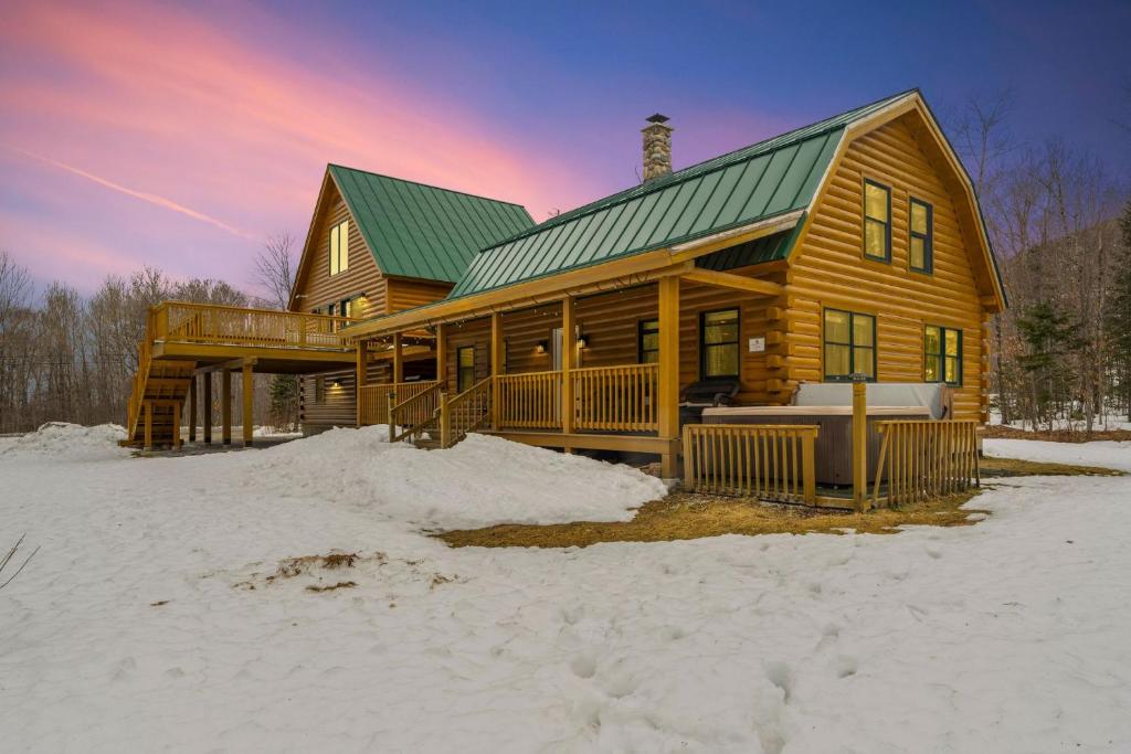 ein Holzhaus mit grünem Dach im Schnee in der Unterkunft The Log Castle Hot Tub 10 Minutes to Skiing in Killington