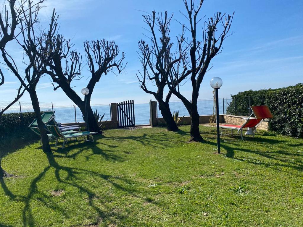 ein Park mit einer Bank und Bäumen im Gras in der Unterkunft Fronte Mare Villa Acquasanta zona "LA FIUMETTA" Terracina in Terracina