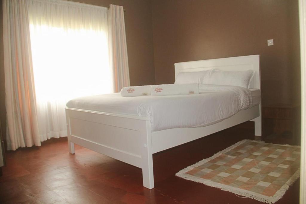 a white bed in a room with a window at Chaka Homes in Kiganjo
