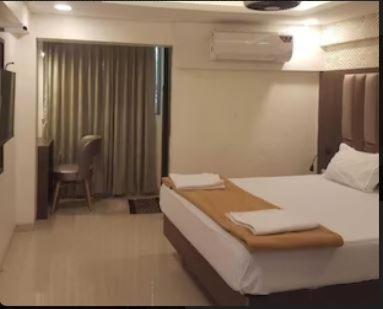 1 dormitorio con 1 cama y 1 silla en una habitación en HOTEL GODAVARI INN en Mire