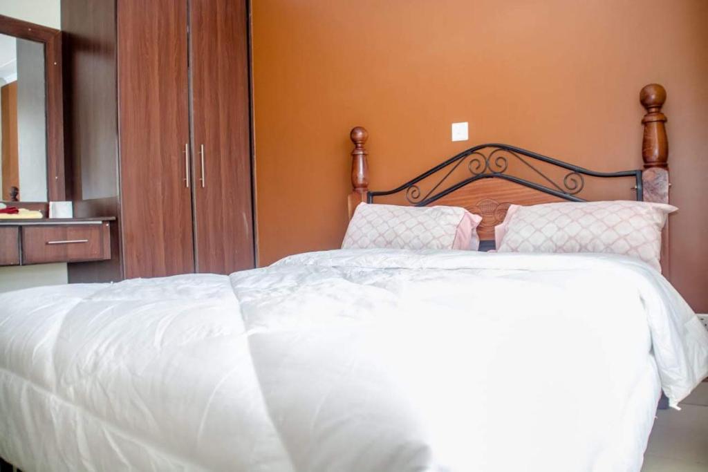 Una cama con sábanas blancas y almohadas en un dormitorio en Sp Accommodations en Mombasa
