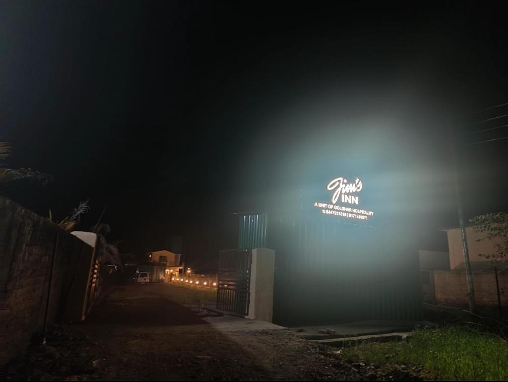 una señal encendida en el lateral de un edificio por la noche en Jim's Inn en Rāmnagar