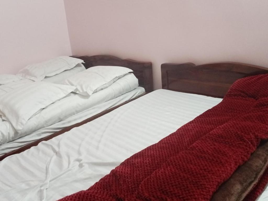 2 camas sin hacer en un dormitorio con manta roja en Nhà nghỉ bình dân Huy Nhung, en Ha Giang