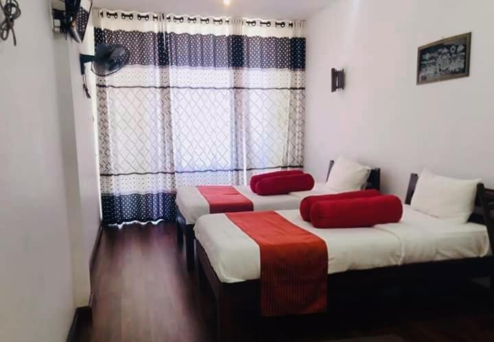 2 posti letto in una camera con lenzuola rosse e bianche di Discovery Retreat Blackwood a Beragala