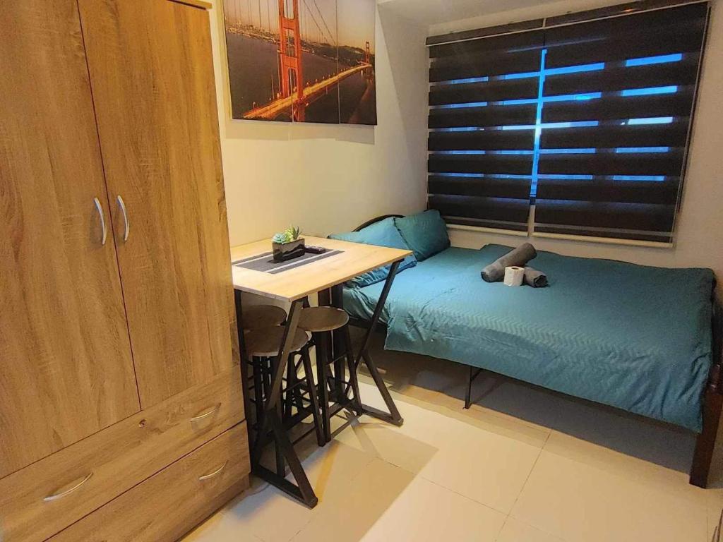 マニラにあるCozy Condo near US EmbassyErmita Manila/ Roxas blvd/ Dolomite beachのベッド、テーブル、デスクが備わる小さな客室です。