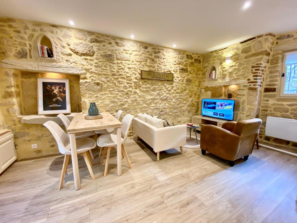 een woonkamer met een tafel en stoelen en een televisie bij Montignac-Lascaux - Les Pierres De Lascaux in Montignac