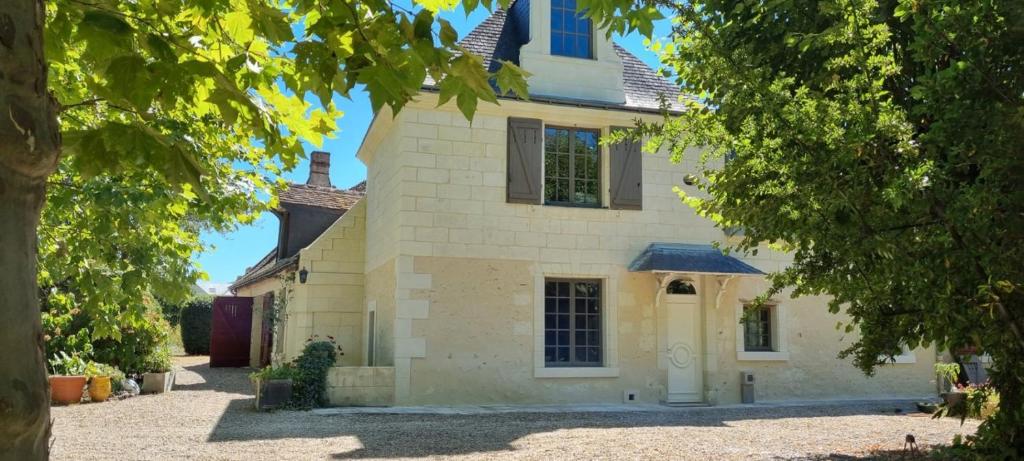 uma grande casa branca com uma entrada e árvores em La Sorellerie em Saint-Avertin