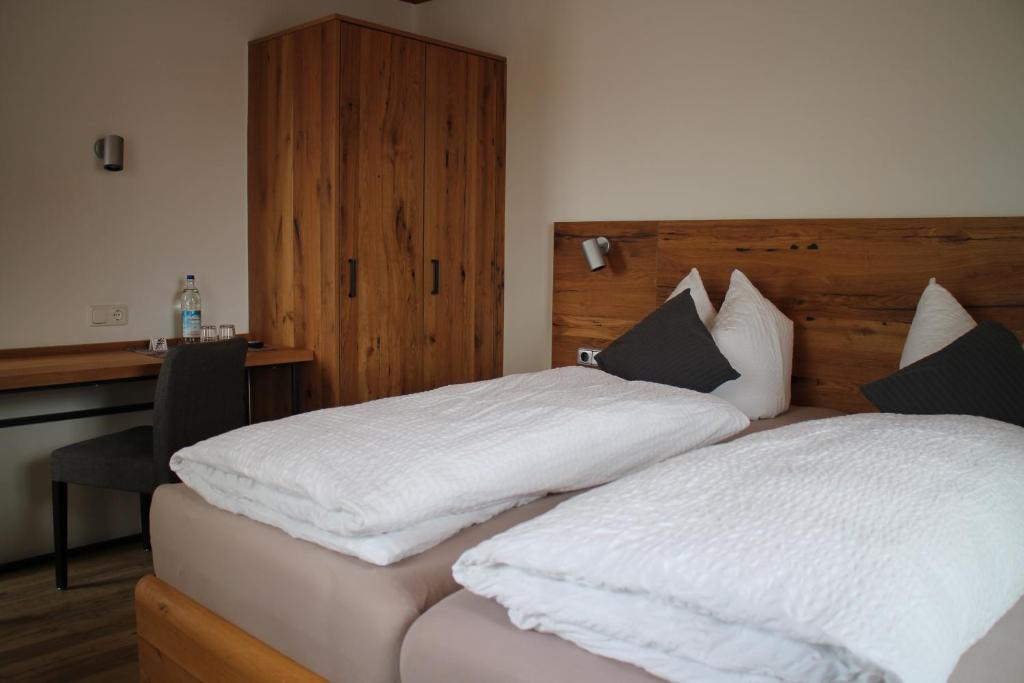a bedroom with two beds with white sheets and a desk at Gasthaus zum Stausee in Grafenau