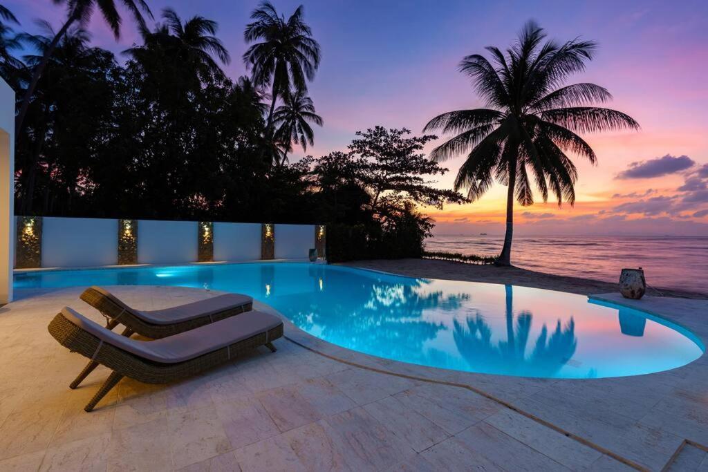 - une piscine avec un lit et une vue sur l'océan dans l'établissement 塔羅别墅-直通海滩的三卧海滨别墅, à Koh Samui 