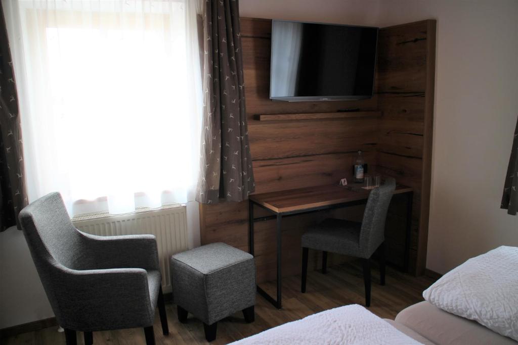a hotel room with a desk and a tv on a wall at Gasthaus zum Stausee in Grafenau