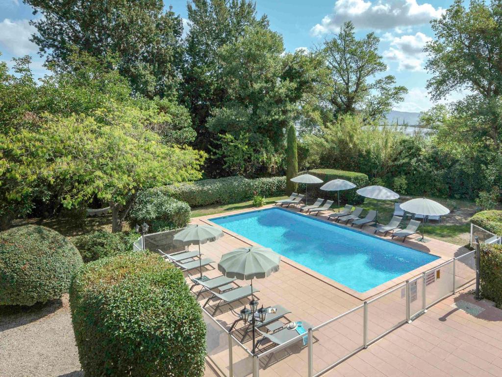 een zwembad met stoelen en parasols ernaast bij Mercure Cavaillon in Cavaillon