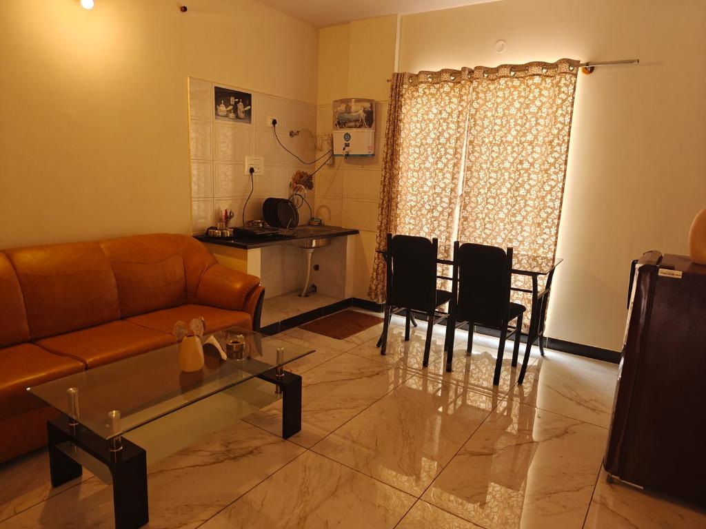 sala de estar con sofá, mesa y sillas en The Whispering Willows, en Mysore