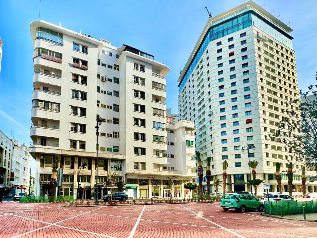 twee hoge gebouwen met auto's geparkeerd op een parkeerplaats bij Casablanca Central Suites - Casa Port in Casablanca