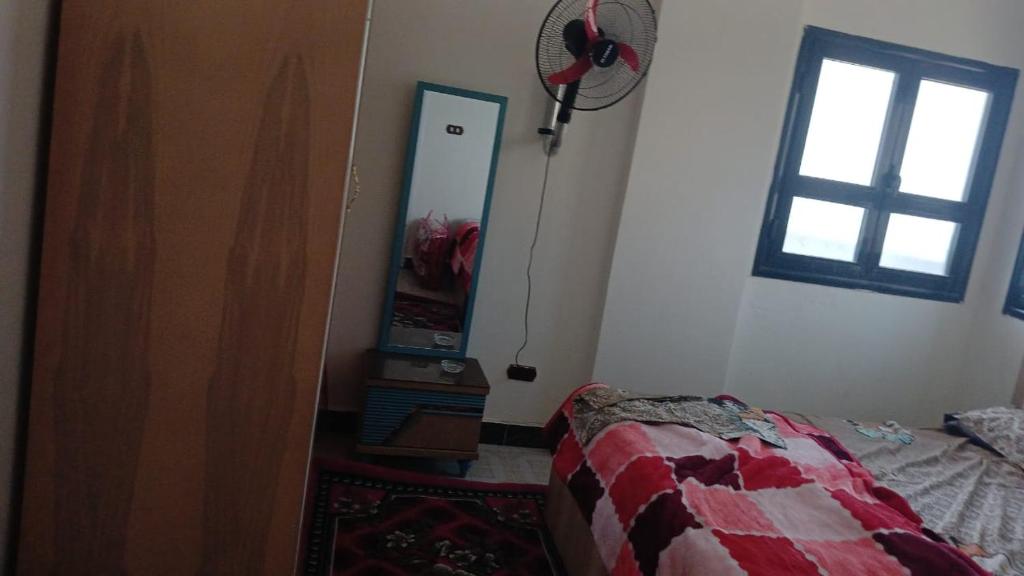 1 dormitorio con cama, espejo y ventana en الاسكندريه العجمي/اكتوبر شاطئ النخيل, en Alejandría