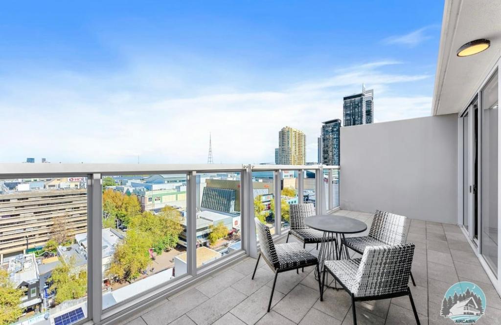 a balcony with a table and chairs and a city skyline at 2 beds luxury apartment in the heart of chatswood12 in Sydney