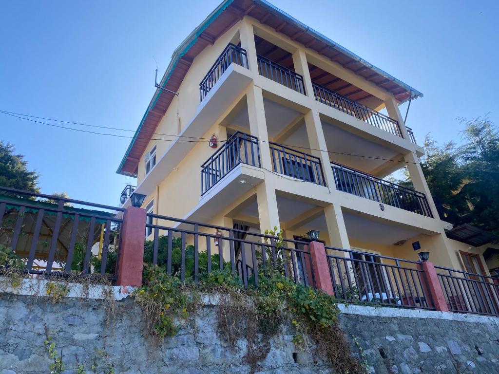 a large building with balconies on top of a wall at Khushi Cottage in Mukteswar