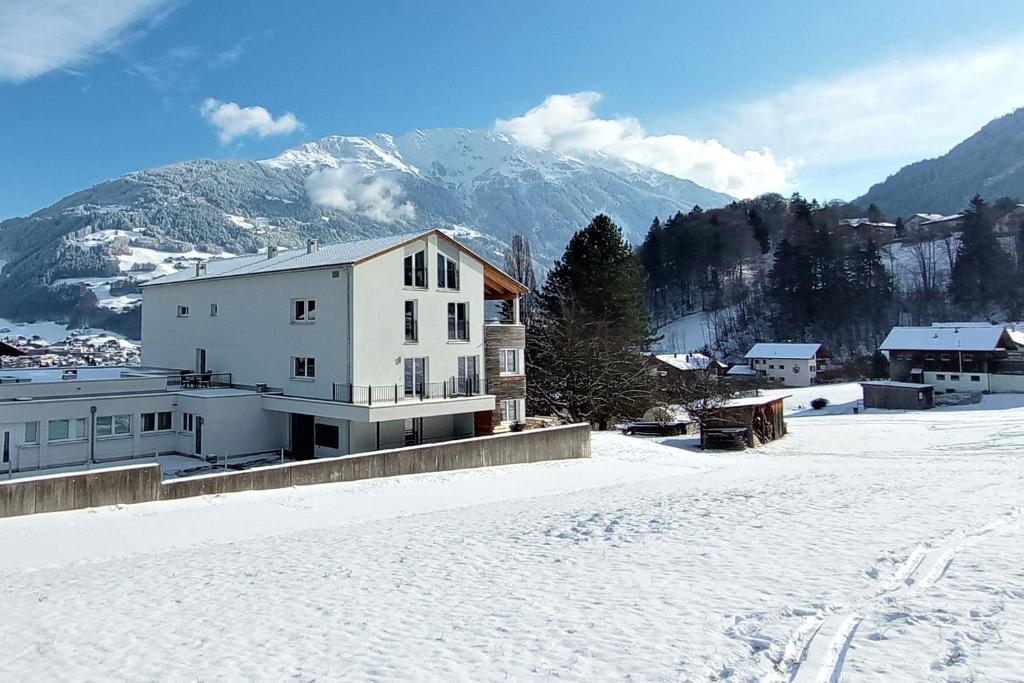 uma casa branca na neve com uma montanha em Drei Türme 2 em Schruns