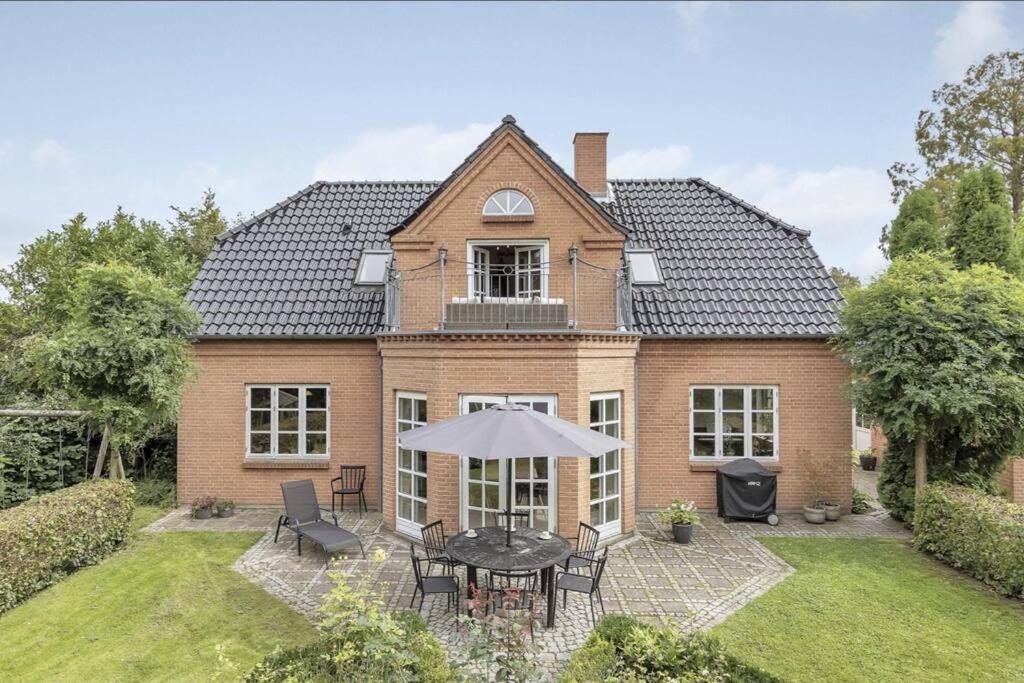 a brick house with a table and chairs in the yard at Nyere villa nær by, skov, strand in Højbjerg